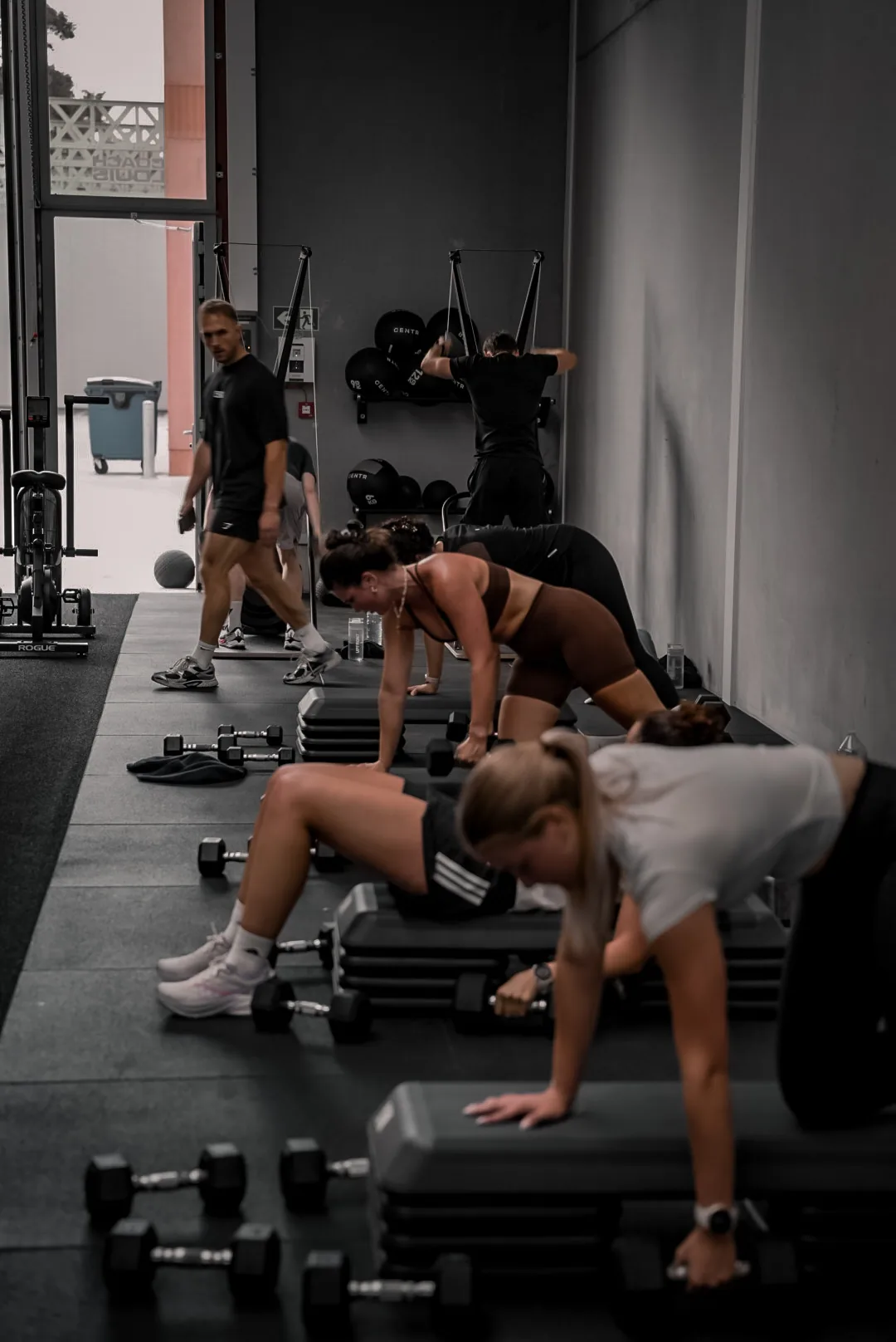 Groepsles bij Coach Louis in Kortrijk waar deelnemers dumbbell rows doen terwijl de coach rondloopt.